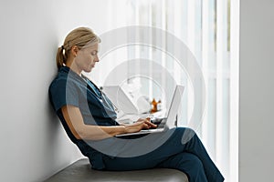 Female healthcare worker using laptop while working at doctor& x27;s office