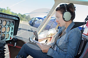 Female helicopter pilot reading manual while sitting in cockpit