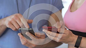 Female and her personal trainer synchronizing cellphones before starting workout