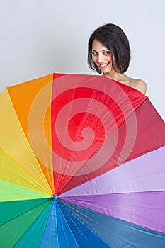 Female hiding over rainbow umbrella