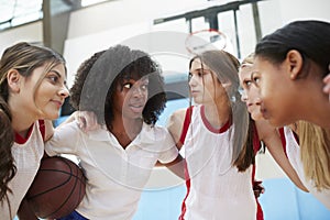 Female High School Basketball Players In Huddle Having Team Talk With Coach