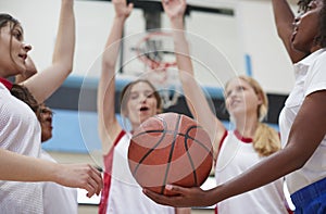 Female High School Basketball Players Joining Hands During Team Talk With Coach