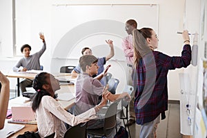 Female High School Pupil Writing On Whiteboard In Class