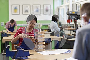 Female High School Student Building Lamp In Woodwork Lesson