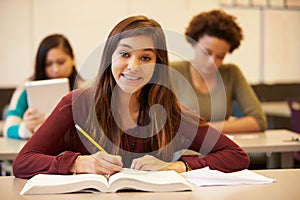 Female High School Student Studying At Desk In Classroom