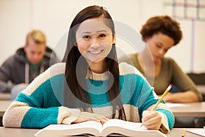 Female High School Student Studying At Desk In Classroom