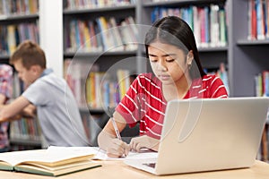 Female High School Student Working At Laptop In Library