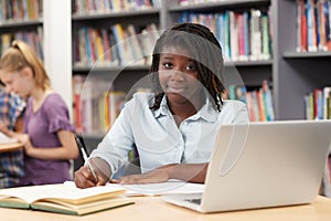 Portrait Of Female High School Student Working At Laptop In Library