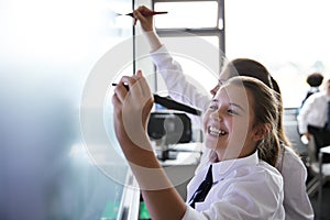 Female High School Students Wearing Uniform Using Interactive Whiteboard During Lesson