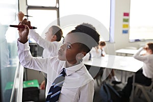 Female High School Students Wearing Uniform Using Interactive Whiteboard During Lesson