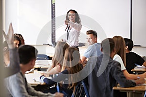 Female High School Teacher Asking Question Standing By Interactive Whiteboard Teaching Lesson