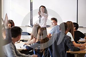Female High School Teacher Asking Question Standing By Interactive Whiteboard Teaching Lesson photo