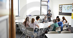 Female High School Tutor Standing By Table With Students Teaching Lesson photo