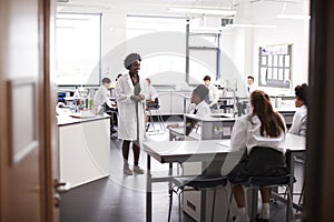 Female High School Tutor Teaching High School Students Wearing Uniforms In Science Class