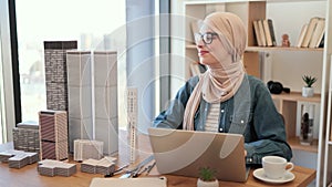 Female in hijab replacing building models on office desk