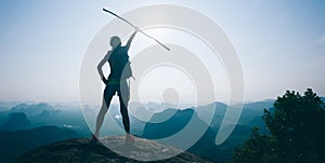 female hiker cheering on mountain top cliff edge