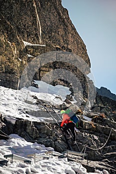 Female hiker climbing up to the Rysy mountain peak at winter
