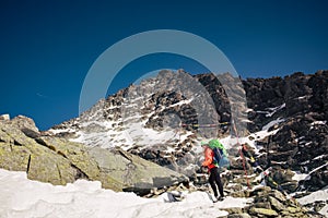 Female hiker climbing up to the Rysy mountain peak at winter