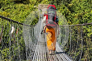 Female hiker crossing a suspension bridge.