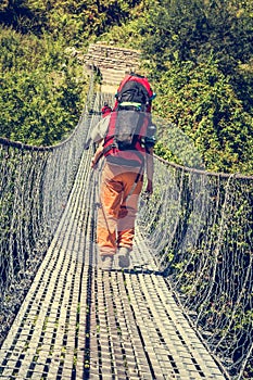 Female hiker crossing a suspension bridge.