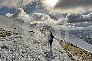 Female hiker descending a snow covered Helvellyn