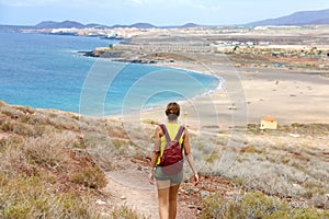 Female hiker descent the pathway with spectacular landscape of Playa la Tejita beach, Tenerife, Canary Islands photo