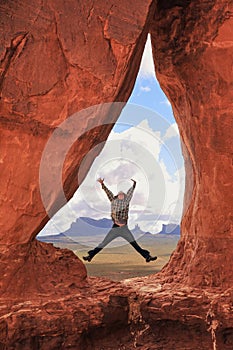 Female hiker jumping inside Teardrop Arch in Southern Utah