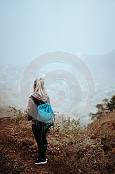 Female hiker looking down over a vertiginous misty ridge on the route to Coculi. Santo Antao Cape Verde