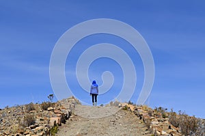 A female hiker on a mountain path, trail, sunny day, Titicaca Lake