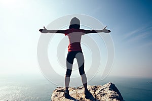 Female hiker open arms on sunrise windy coast