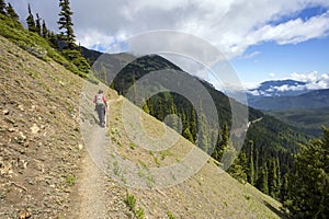 Female hiker with pole on mountain ridge path