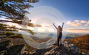 Female Hiker Raising Arms to the sun setting over a beautiful vista at the top of an Appalachian  mountain