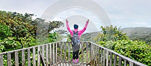 female hiker raising hands high up