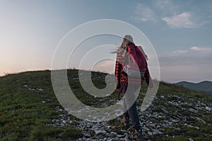 Female hiker silhouette walking the trail uphill, at sunset