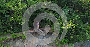 Female hiker standing on cliff in forest 4k