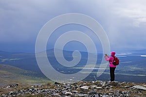 Female hiker taking mobile phone photo on fell top