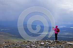 Female hiker taking mobile phone photo on fell top photo
