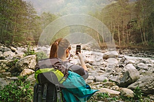 Female hiker taking photo of Himalayan river Modi Khola