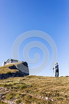 Female hiker taking photos of a house atop Schafberg in Salzburg, Austria