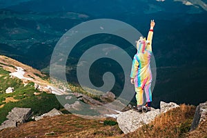 Female hiker in unicorn costume celebrating success in mountains