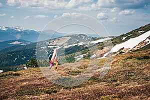 Female hiker in a unicorn costume in mountains in Spring