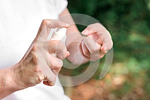 Female hiker using antiseptic spray outdoors photo