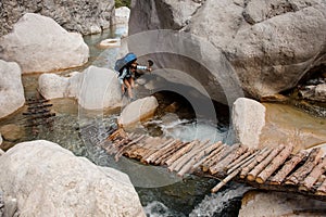 Female hiker wades through river between cliffs