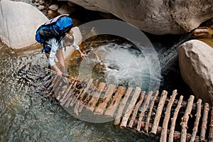 Female hiker wading through river between cliffs