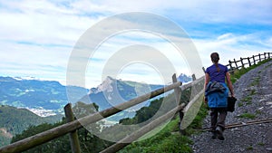 Female hiker walking along a country road with a great view of a mountain landscape