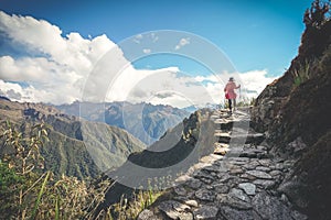 A female hiker is walking on the famous Inca trail of Peru with walking sticks. She is on the way to Machu Picchu photo