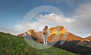 Female hiker walking in mountains. Blue sky with cloud