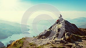 Female hikers on top of the mountain taking a break and enjoying a valley view