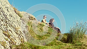 Female hikers on top of the mountain taking a break and enjoying a valley view