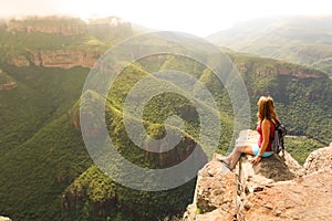 Female hiking tourist sitting on mountains and enjoying the view